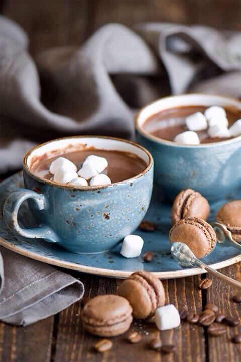 Tazas de chocolate azules, con chocolate caliente y nubes, sobre un plato azul